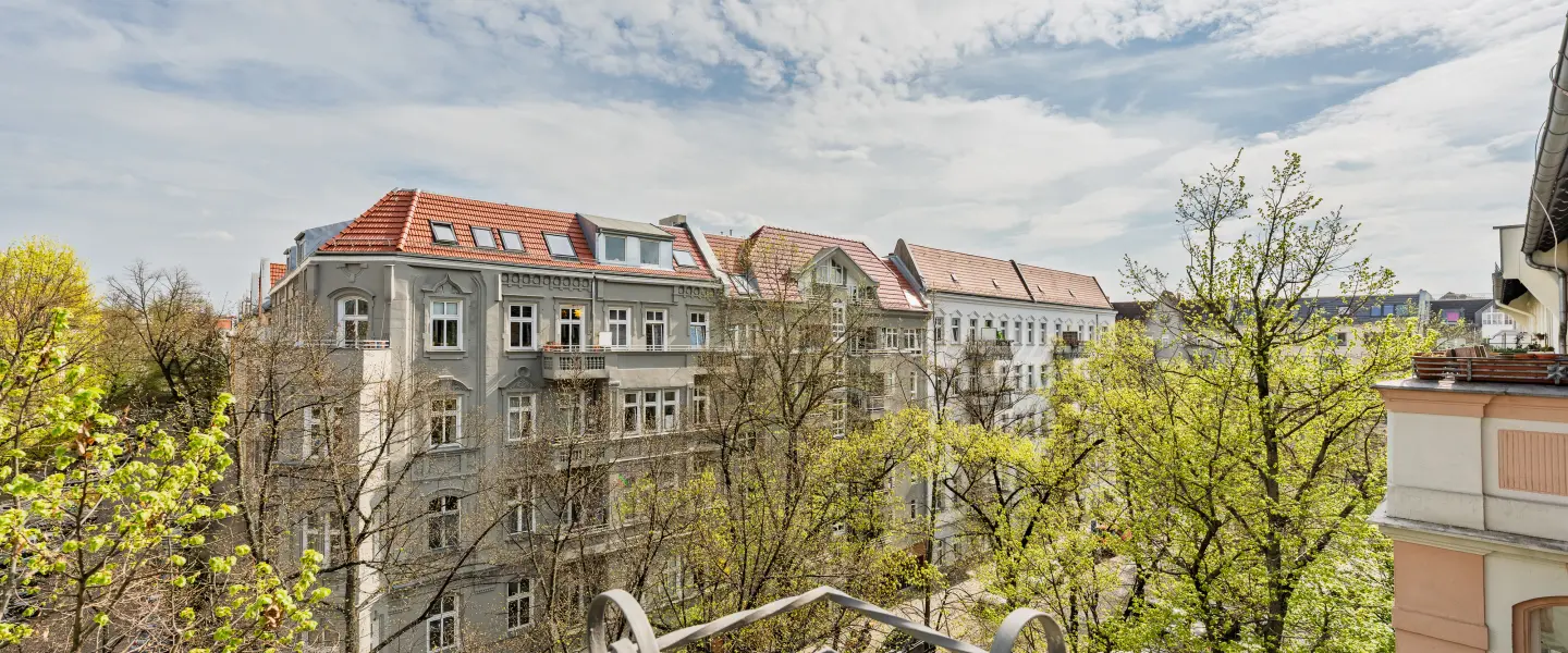 Ausblick vom Balkon auf Altbauten und Bäume